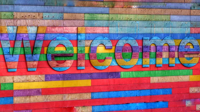 Bunte Holzwand mit ausgeschnittenen „Welcome“-Buchstaben.